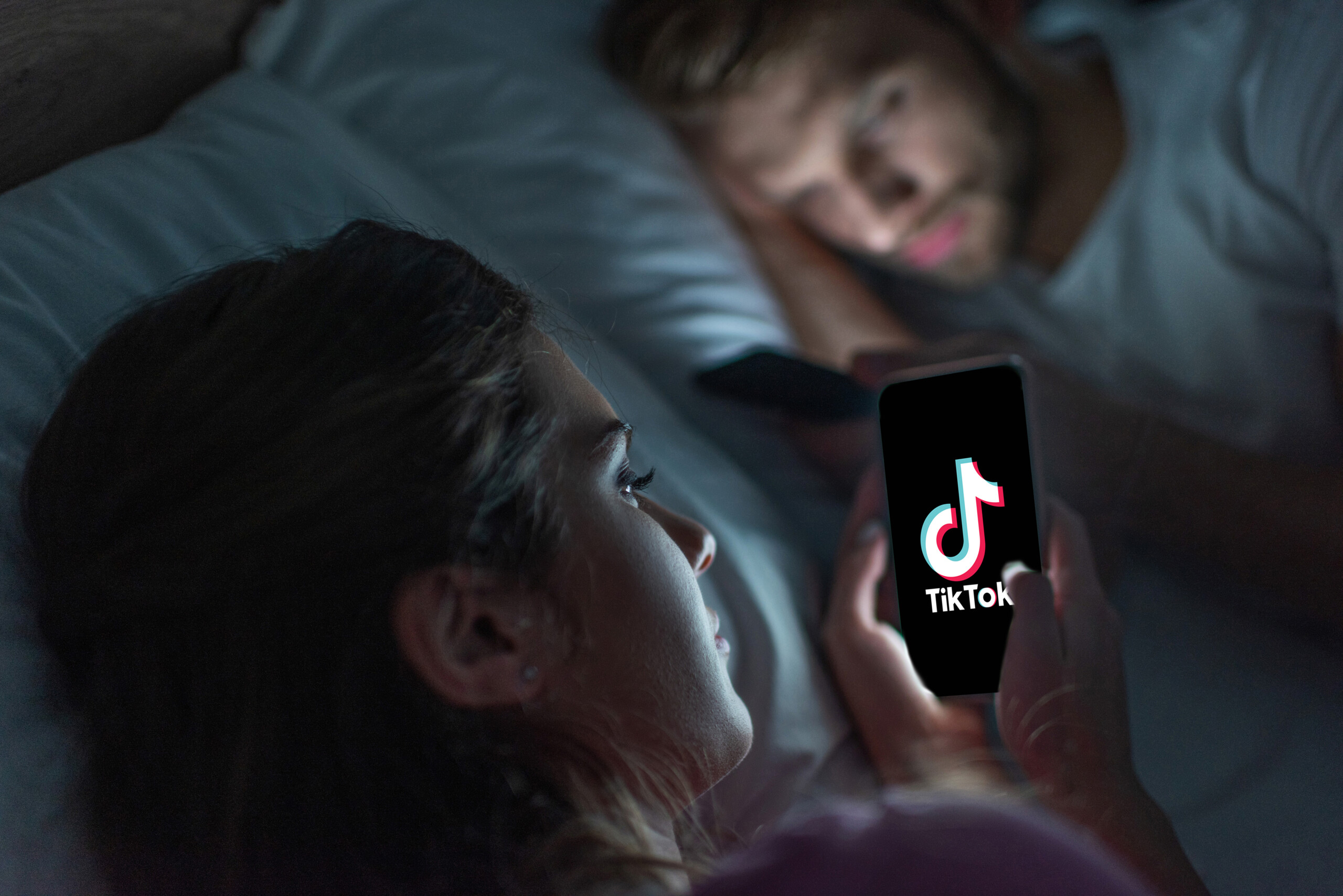 Vrouw en man zitten op Tiktok/ social media terwijl ze in bed liggen